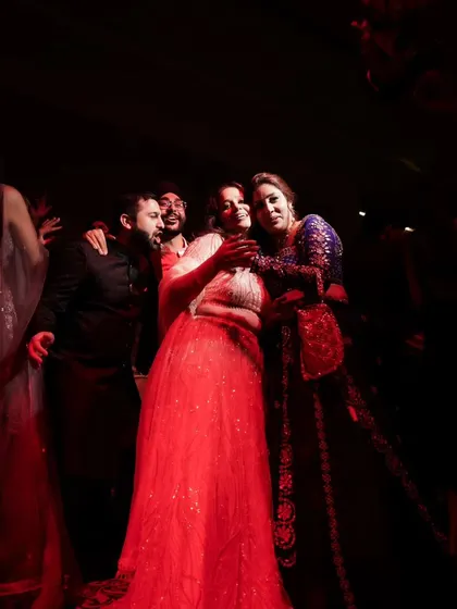 A candid moment under the red lights of the dance floor. The lighting creates a vibrant and energetic mood for this group photo.