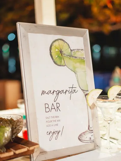 A classic margarita bar is always a crowd pleaser. The hand painted sign and fresh garnishes make it an inviting spot for guests to grab a cocktail and mingle.