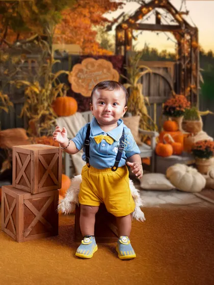 Our themed sessions can match any season. This autumn-inspired setup with pumpkins and warm colors creates a cozy and charming portrait for this happy little boy.