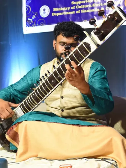A full view of my posture while playing the sitar. The instrument rests on my foot, allowing for stability and comfort during long performances.