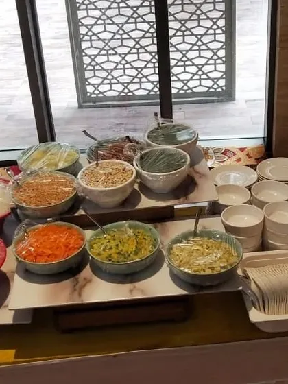 A look at the fresh and organized ingredients for a Khao Suey live counter. Guests can build their own bowl with a variety of noodles, vegetables, and condiments.
