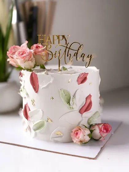 A minimalist birthday cake with an abstract, painted floral design and fresh roses. This artistic style is perfect for modern, chic celebrations.