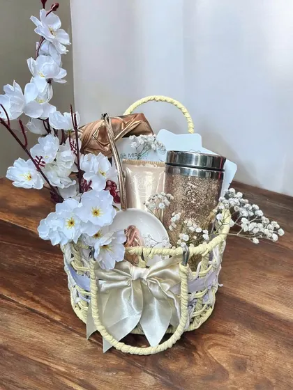 An elegant and dreamy gift basket in white and gold. This hamper includes a glittery tumbler and other coordinated items, decorated with delicate white flowers and a satin bow.