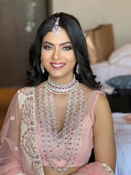 A radiant smile from this beautiful bride. This close-up shows her flawless makeup, featuring shimmery eyeshadow, long lashes, and a perfectly matched lip color, all framed by sparkling diamond jewellery.