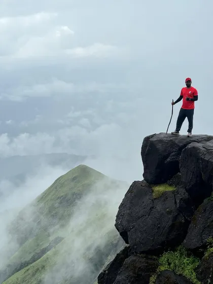 A trek lead stands at a viewpoint on Kumara Parvatha, taking in the misty peaks. Our experienced guides know the trail like the back of their hand.