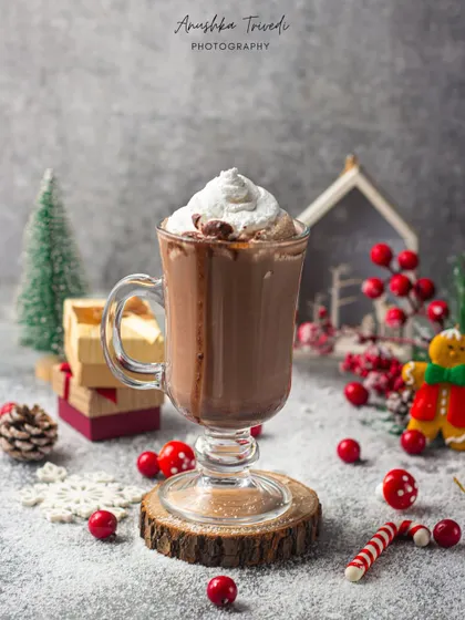 A classic hot chocolate for Christmas, styled with candy canes and festive red berries in a snowy setting.
