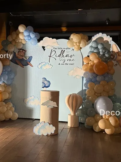 For the little pilot's first flight, this "Urso Aviador" or Aviator Bear theme is perfect. The setup features a personalized backdrop, a large light-up number one, and adorable teddy bear and hot air balloon props.