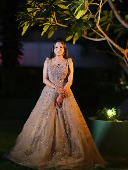 A full-length shot of a client in a beautiful golden gown, ready for a reception. The makeup is soft and glowing to match the elegance of her dress.