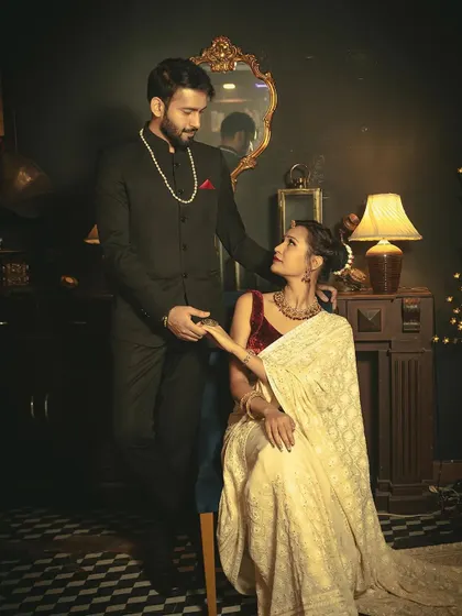 An elegant, posed shot in a classic, dark-toned room, capturing a moment of gentle connection between the couple.