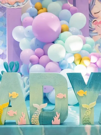 Custom-painted marquee letters spelling out "AADYA," decorated with little fish and mermaid tails for an under-the-sea party.
