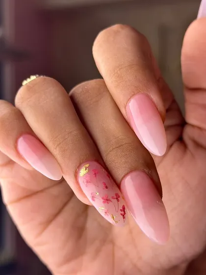 A delicate and dreamy look with tiny, hand-painted red flowers and gold flakes embedded within a translucent pink nail. It's like a secret garden on your fingertips.