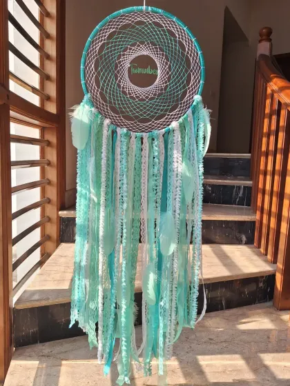 The deep teal green of this dreamcatcher, personalized with our brand name, offers a sense of tranquility. It's designed to be a symbol of protection and positivity in your space.