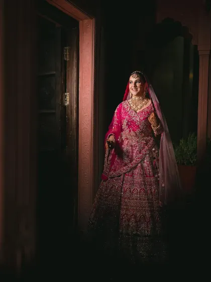 A stunning shot of the bride making her entrance. The dramatic lighting and her gorgeous pink lehenga create a truly magical moment.