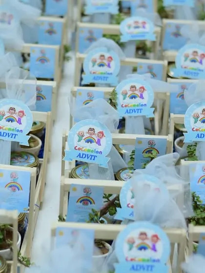 Adorable Cocomelon-themed return gifts, complete with personalized tags and small plants, arranged in wooden crates.