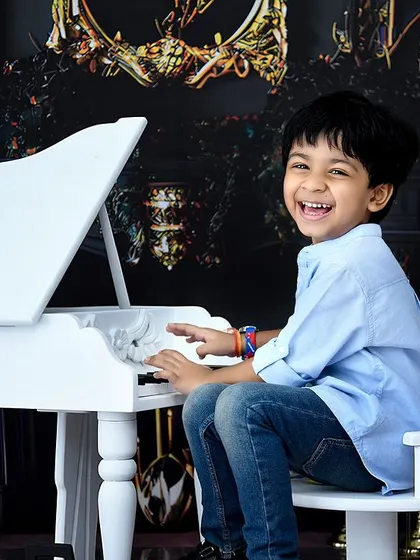 A huge, happy smile is the best music. This older boy is having a great time during his playful piano photoshoot.