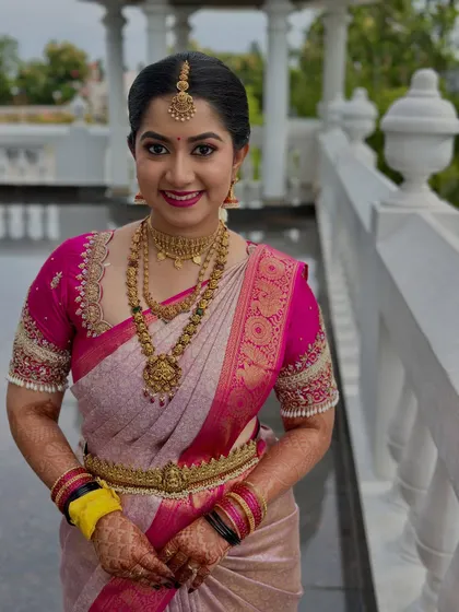 A smiling bride looking radiant in her pink Kanjeevaram saree. Her makeup is fresh and bright, with a matching pink lip and defined eyes, perfect for a daytime wedding ceremony.