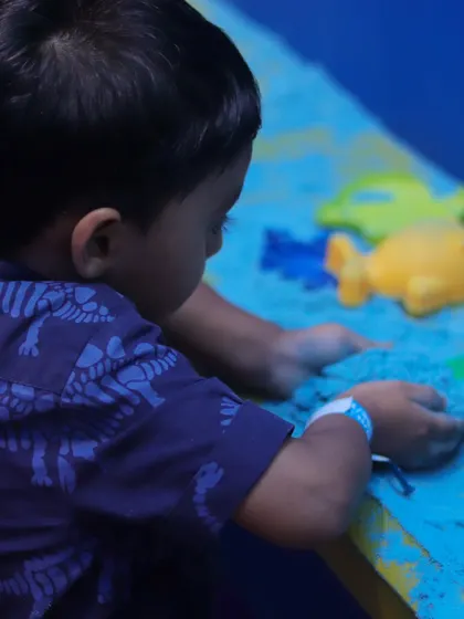 Our sensory sand pit offers a clean and creative play experience. Here, a young child is using molds to create shapes, which is great for developing fine motor skills.