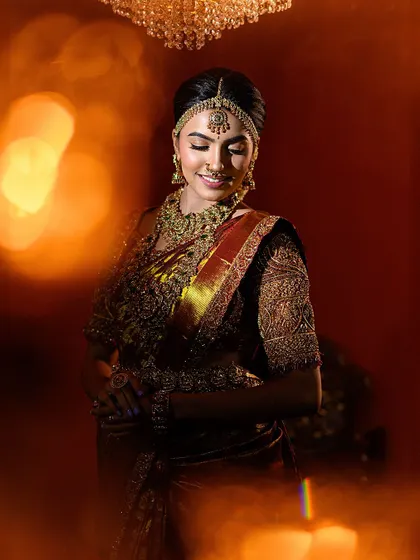 The bokeh effect from the foreground lights adds a magical touch to this bridal portrait. It highlights the bride's happy expression and the richness of her wedding attire.