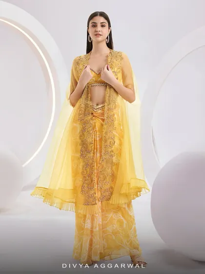 Our RUMI Cape Set in a vibrant yellow, featuring a knotted skirt, a blouse, and a sheer organza cape with abstract embroidery.