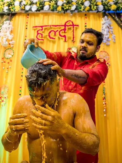 The ritualistic pouring of water during the Haldi ceremony, captured at the perfect moment to show the splash and the groom's reaction.