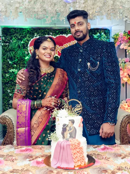 The happy couple posing with their beautifully designed engagement cake, which features a custom illustration of them.