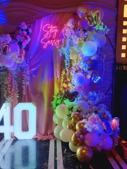 "Stay Sassy" at 40! This glamorous 40th birthday backdrop combines a neon sign, light-up numbers, and a beautiful arrangement of balloons and flowers for a truly fabulous celebration.