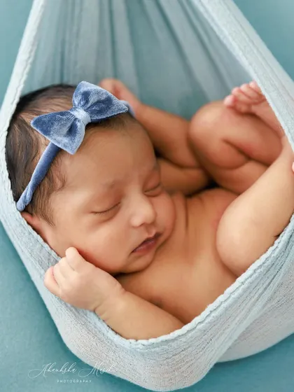 A duplicate image, this shot of a newborn in a blue sling perfectly captures the safe, curled "womb" pose that is so characteristic of the first few days.