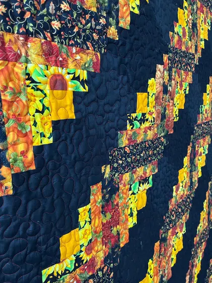 A detail shot of a Log Cabin quilt, showing the dense quilting on the black fabric.