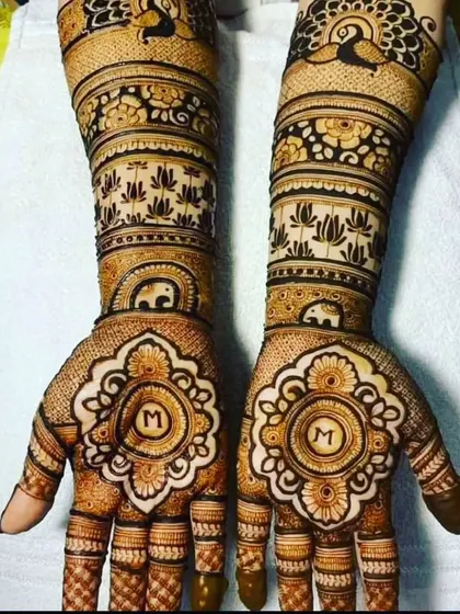 A symmetrical design featuring the initial 'M' inside a beautiful mandala on both palms, surrounded by lotus and peacock patterns.