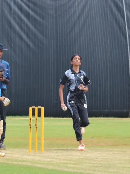 A young bowler completes her action, having given her all in the delivery.