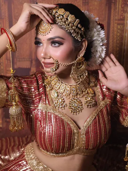 A full shot of the bride in a red and gold lehenga, showcasing the entire golden jewellery set, including the kalire.