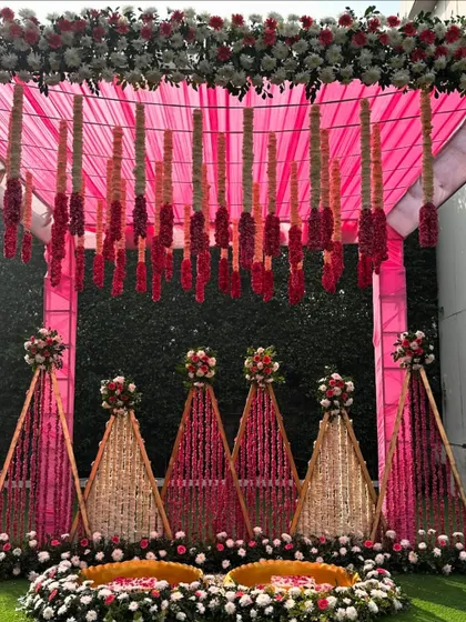 A detailed shot of our pink Haldi mandap, showing the hanging floral tassels and the intricate flower arrangements on the triangular back panels.