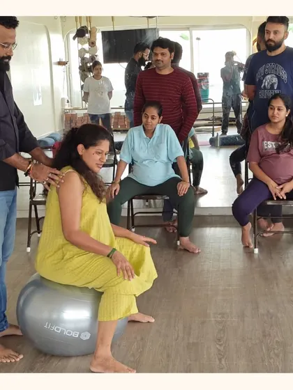 A guru provides hands-on guidance to an expectant mother using a stability ball. These sessions are designed to improve pelvic mobility and ease discomfort, preparing the body for a smoother birth.