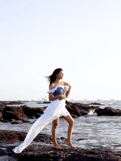 A stunning wide shot of a custom-designed beach outfit, featuring a blue corset and a flowing white skirt against the sea.