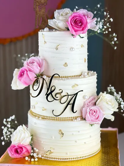 Pure elegance for your big day. Our best-selling white and pearl wedding cake, adorned with soft pink roses and delicate baby's breath, is the perfect blend of classic charm and modern romance.