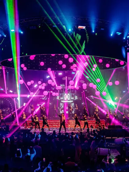 A wide shot of a spectacular sangeet performance. The lasers, lights, and dancers create a high-energy, concert-like atmosphere that we love to capture in all its glory.
