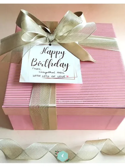 A lovely pink striped box tied with a shimmering gold ribbon. The packaging itself is a gift and sets the tone for the wonderful surprises inside.