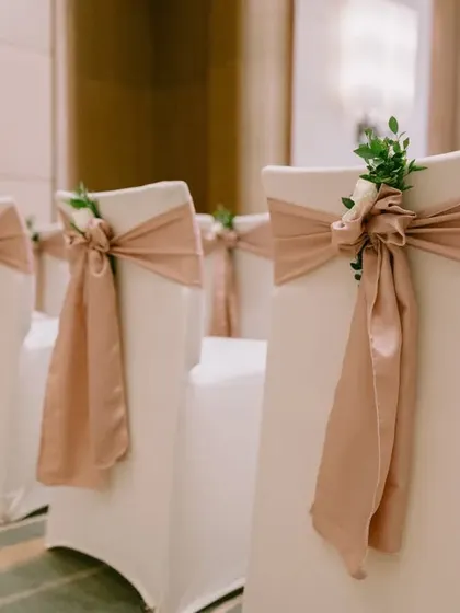 Even the chairs are part of the story. For this event, I used elegant chair covers with dusty rose sashes and a sprig of greenery for a refined touch.