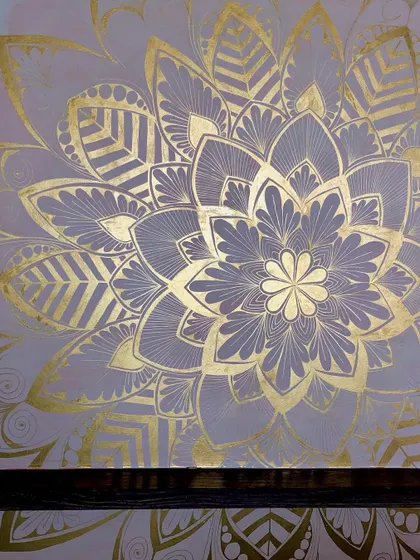 A close up of a gold leaf mandala on a lavender grey wall. The way the metallic leaf catches the light is just magical.