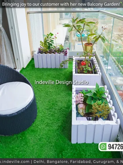 Another view of the balcony, showing the arrangement of planters and the comfortable wicker chair. The glass railing ensures an unobstructed view of the city.