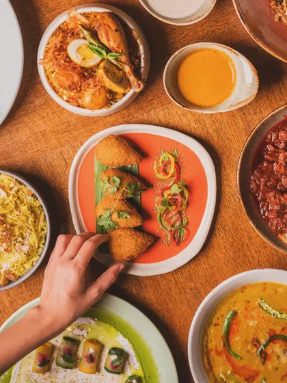 Capturing the communal joy of food. A hand reaching for an appetizer in a large spread adds a human element, transforming a food photo into a story of a shared meal.
