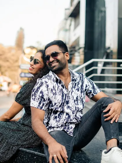 A fun and relaxed portrait of the couple sitting back-to-back on a city sidewalk.