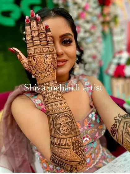A happy client showing off her intricate mehendi, which features a mix of traditional patterns and peacock motifs.