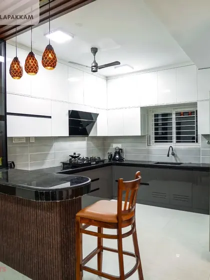 A wide shot of the Sithalapakkam villa kitchen, showing the breakfast bar with its elegant curved countertop and fluted panel base. The pendant lights add a touch of warmth and style.