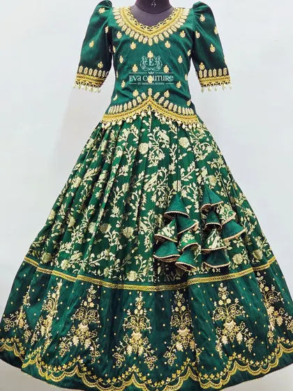 For a truly grand occasion, this emerald green velvet lehenga is a showstopper. The entire set is covered in heavy gold maggam work, from the detailed blouse to the borders of the full-flared skirt, creating a regal look for your little one.