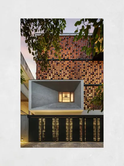 The monolithic concrete volume of the Kamala Residence facade, framed by the terracotta screen and an existing tree, creates a powerful architectural composition.