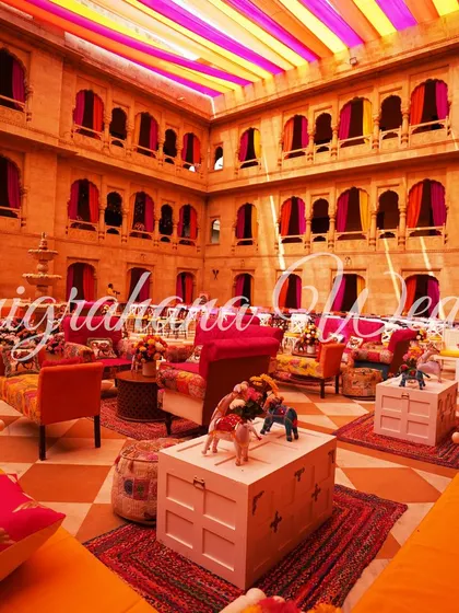 The lounge-style seating with colorful cushions and rustic trunks as tables, perfect for a relaxed Mehendi.