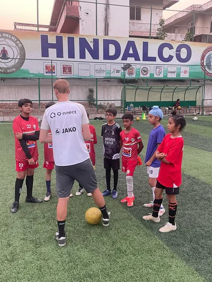 A coach from VfB Stuttgart addresses a group of young players under the Hindalco banner, one of our proud supporters. These camps are a collaborative effort to elevate the standard of youth football in India.