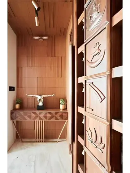 An entryway with rich wood textures on the wall and a custom console table. The intricately carved door on the right adds a traditional and artistic element.