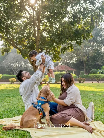 A wide shot of a happy family enjoying a picnic in the park with their cocker spaniel.